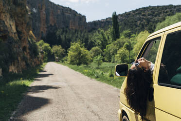 Frau streckt an einem sonnigen Tag den Kopf aus dem Fenster eines Lieferwagens, Aragonien, Spanien - DAMF01008