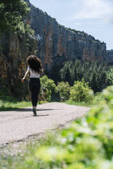 Carefree woman walking on road at sunny day in Aragon, Spain - DAMF01015