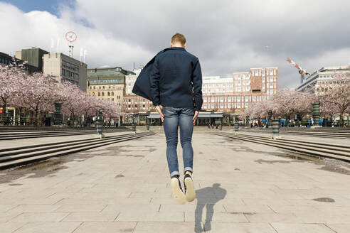 Junger Mann springt auf einem öffentlichen Platz - FOLF11730
