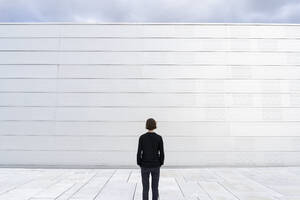 Rückansicht eines Teenagers an einer weißen Wand - FOLF11836