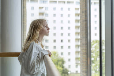 Teenage girl at railing looking out window - FOLF11842