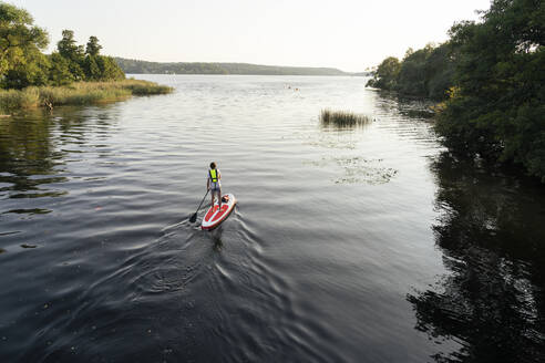 Young man paddleboarding on lake - FOLF11850