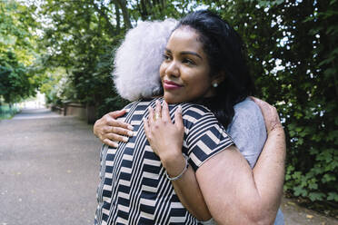 Mother and daughter hugging each other in park - ASGF02503