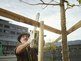 Älterer Gärtner baut Zaun um frisch gepflanzten Baum - CVF02052