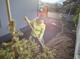 Young gardeners digging mud for maintenance on sunny day - CVF02055