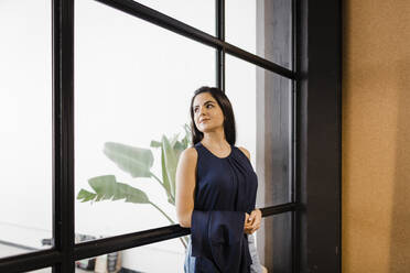 Contemplative businesswoman leaning on glass wall - DCRF01345