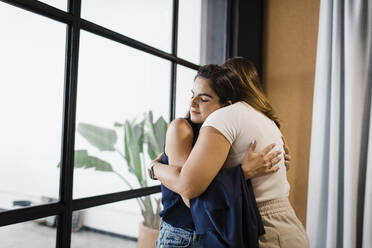 Businesswomen hugging each other in office - DCRF01346