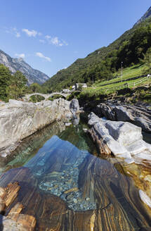 Schweiz, Tessin, Lavertezzo, Verzasca Fluss fließt durch Valle Verzasca im Sommer mit Ponte dei Salti Bogenbrücke im Hintergrund - GWF07500