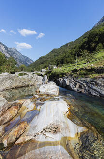 Schweiz, Tessin, Lavertezzo, Verzasca Fluss fließt durch Valle Verzasca im Sommer mit Ponte dei Salti Bogenbrücke im Hintergrund - GWF07501