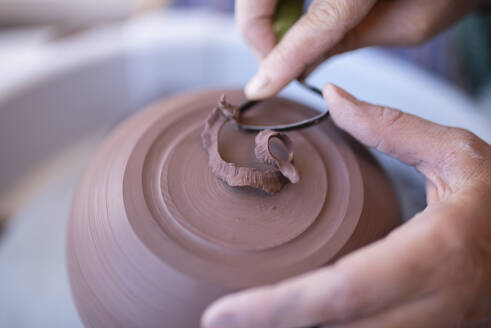 Hands of potter using scraping tool - FOLF11858