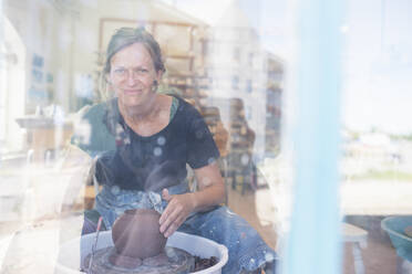 View through window of potter using pottery wheel - FOLF11859