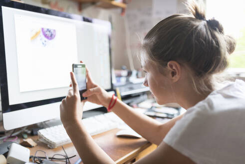 Teenage girl text messaging with smartphone at desk - FOLF11879