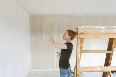 Woman looking at wall in house - FOLF11881