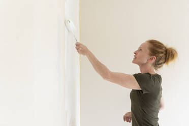 Woman painting wall in house - FOLF11882