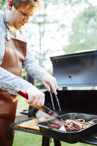 Junger Mann kocht Fleisch auf dem Grill - FOLF11888