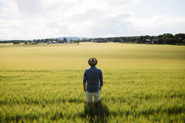 Junger Mann mit Hut steht auf einem Feld - FOLF11889