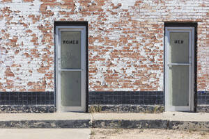 Ein Gebäude mit zwei Türen, beschriftet mit Frauen- und Männertoiletten. - MINF16550