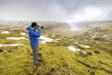 Männlicher Wanderer beim Fotografieren des Fjords Kaldbaksfjordur - WPEF06080