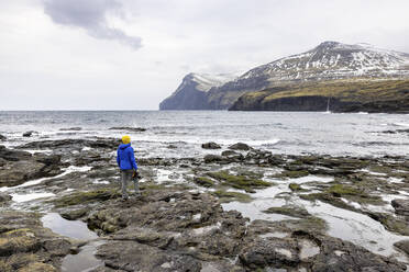 Färöer Inseln, Eysturoy, Eidi, Männlicher Wanderer bewundert Küstenlandschaft - WPEF06083