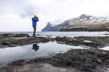 Färöer Inseln, Eysturoy, Eidi, Männlicher Wanderer fotografiert Küstenlandschaft - WPEF06084