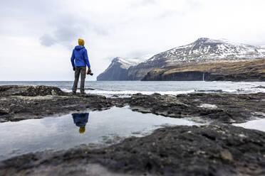 Färöer Inseln, Eysturoy, Eidi, Männlicher Wanderer bewundert Küstenlandschaft - WPEF06085