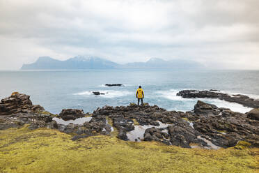 Färöer Inseln, Eysturoy, Gjogv, Männlicher Wanderer bewundert den Atlantik vom Rand einer Klippe - WPEF06092