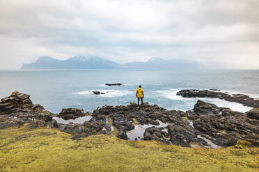 Faroe Islands, Eysturoy, Gjogv, Male hiker admiring Atlantic Ocean from edge of cliff - WPEF06092