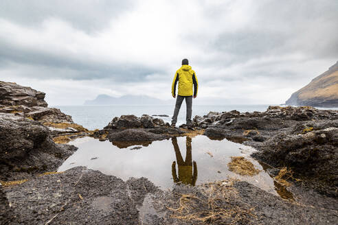 Faroe Islands, Eysturoy, Gjogv, Male hiker admiring Atlantic Ocean from edge of cliff - WPEF06093