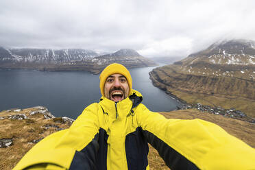 Faroe Islands, Eysturoy, Funningur, Excited hiker taking selfie at Hvithamar vantage point - WPEF06097