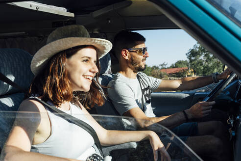 Glückliches Paar sitzt im Van an einem sonnigen Tag - DAMF01024