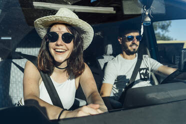 Happy woman wearing hat sitting in van with man - DAMF01026