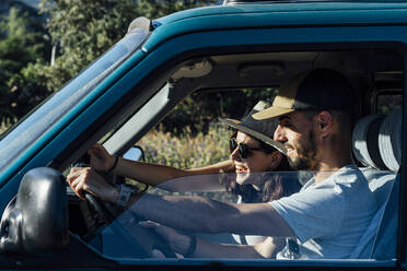 Happy woman enjoying road trip with in van on sunny day - DAMF01027