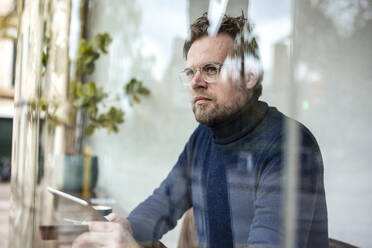 Thoughtful businessman with eyeglasses sitting in cafe - JOSEF11032