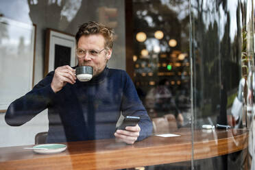 Geschäftsmann mit Smartphone trinkt Kaffee in einem Cafe - JOSEF11040