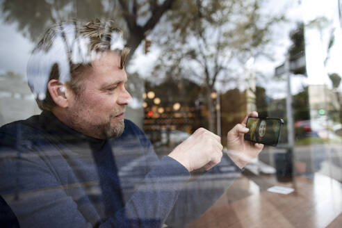 Geschäftsmann macht Videoanruf mit Freundin durch Smartphone im Café - JOSEF11064