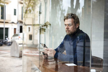 Ernster Geschäftsmann schaut aus dem Fenster und sitzt in einem Café - JOSEF11065