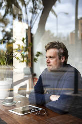 Nachdenklicher Geschäftsmann in einem Café, gesehen durch ein Glasfenster - JOSEF11074