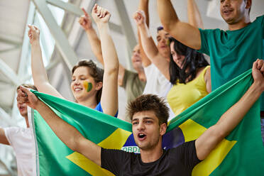 Fans with Brazil Flag shouting together at sports event in stadium - ZEDF04723