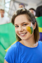 Junge lächelnde Frau zeigt Brasilien Flagge auf Gesicht - ZEDF04727