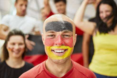 Glücklicher Mann mit deutscher Flagge auf dem Gesicht im Stadion - ZEDF04734