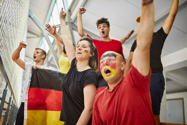 Excited fans cheering together watching sports event in stadium - ZEDF04736