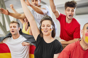 Happy fans with hands raised cheering together at stadium - ZEDF04741