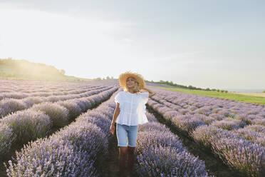 Glückliche Frau mit Hut in einem Lavendelfeld stehend - SIF00262
