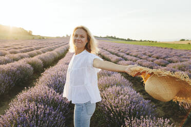 Carefree woman with straw hat enjoying in lavender field at sunset - SIF00266