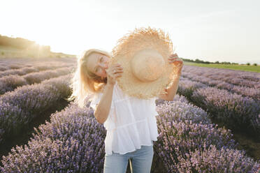 Woman playing with straw hat on lavender field - SIF00274