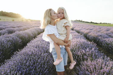 Mutter küsst Tochter in Lavendelfeld bei Sonnenuntergang - SIF00289