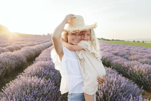 Niedliches Mädchen mit Mutter und Hut in einem Lavendelfeld stehend - SIF00294