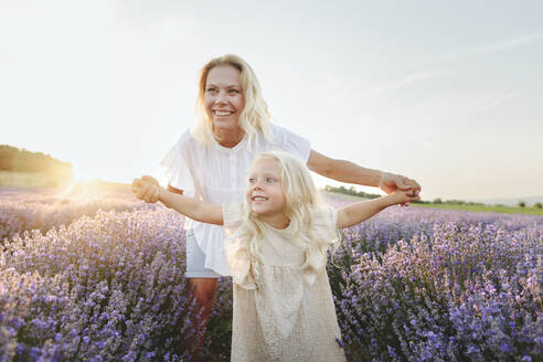 Cute girl with arms outstretched standing in front of mother at lavender field - SIF00301