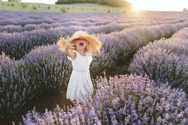 Sad girl wearing hat shouting amidst lavender plants - SIF00302