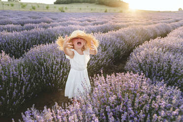 Trauriges Mädchen mit Hut, das inmitten von Lavendelpflanzen schreit - SIF00302